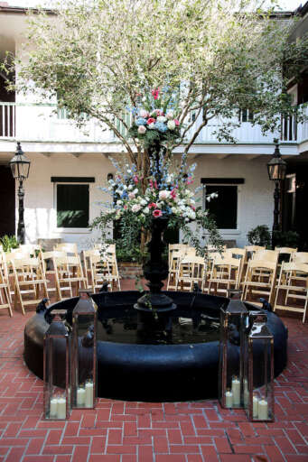 A beautifully decorated courtyard with a fountain, flowers, and seating.