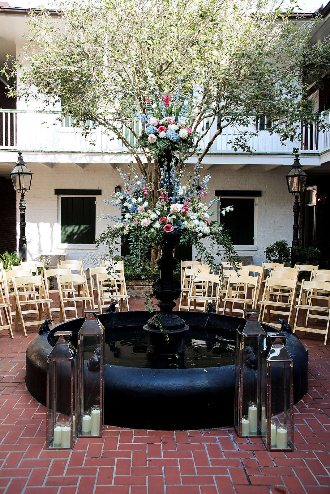 A beautifully decorated courtyard with a fountain, flowers, and seating.
