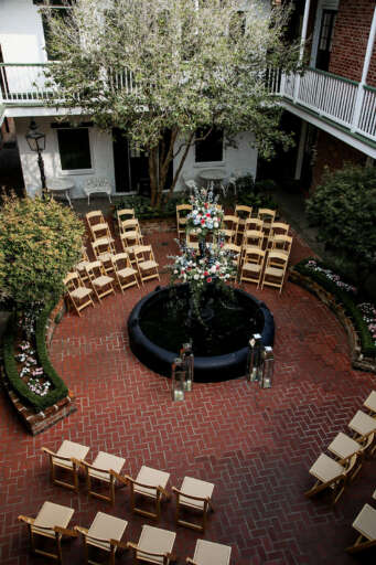 A courtyard with a fountain, flower arrangement, and chairs set up for an event.