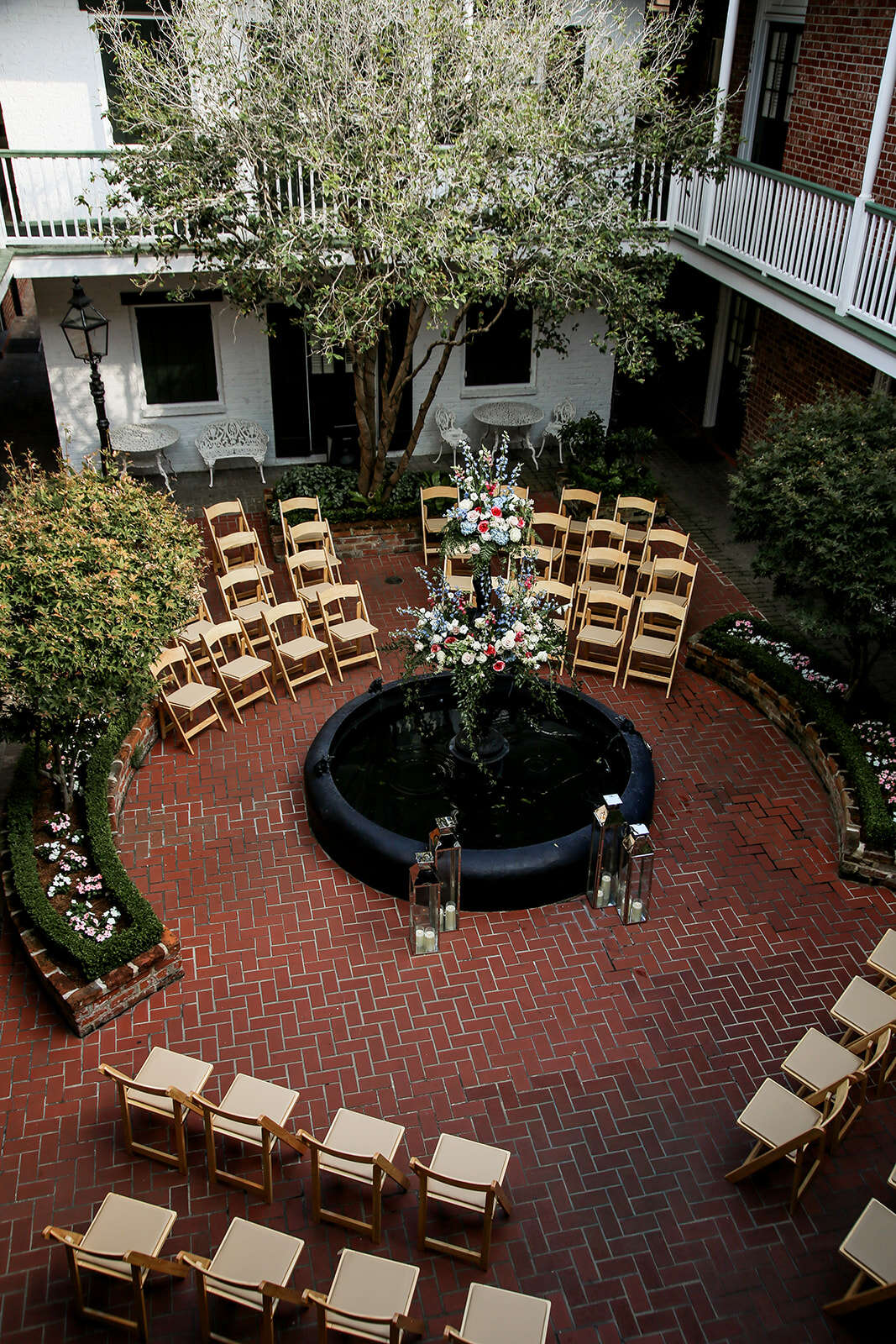 A courtyard with a fountain, flower arrangement, and chairs set up for an event.
