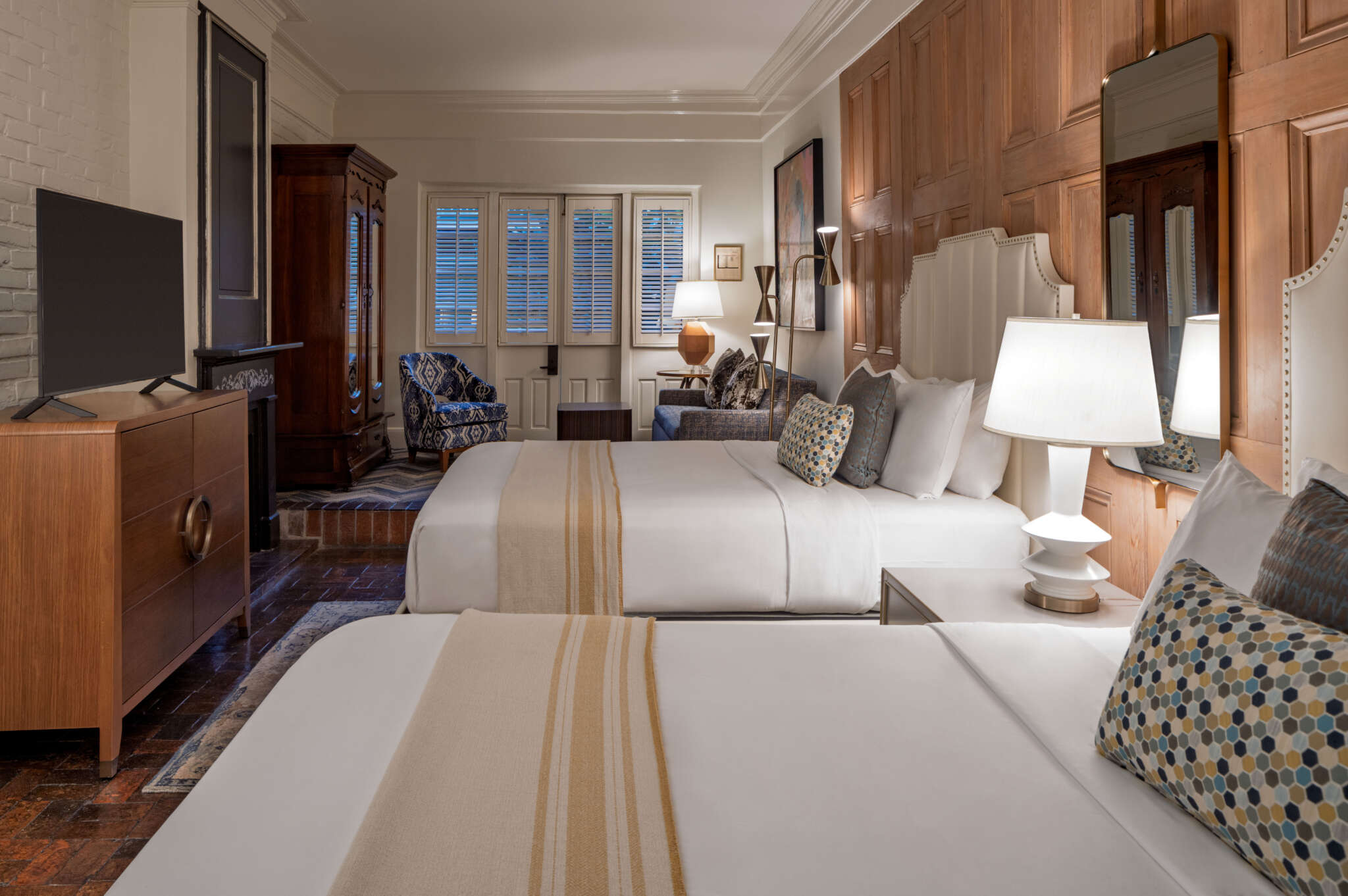 A luxurious hotel room with two beds, a TV, and a sitting area.